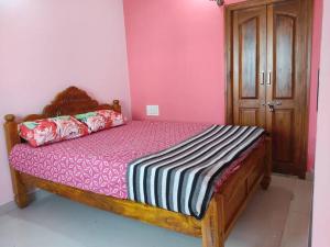 een slaapkamer met een houten bed met roze muren bij Vrindavan - Cozy Stay in Mysore