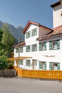 un gran edificio blanco con ventanas verdes y una valla en Haus Alpenblick, en Oetz