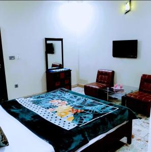 a bedroom with a bed and two chairs and a television at Galaxy Inn in Karachi