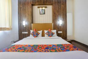 1 dormitorio con 1 cama blanca grande con almohadas coloridas en FabHotel MNG en Kānpur