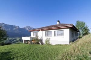 a white house on a hill with mountains in the background at Jambo Pua in Alt Sankt Johann