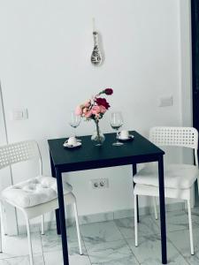 une table noire avec deux verres et un vase de fleurs dans l'établissement Apart Studio Maria - Parcare Privata, à Bucarest