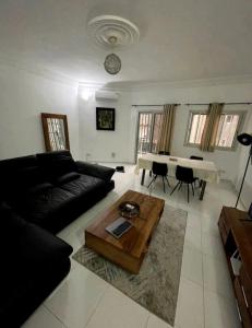 een woonkamer met een zwarte bank en een tafel bij joli appart 2 chambres salon liberté 6 extension in Dakar
