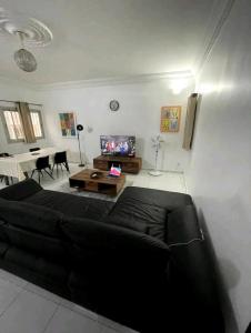 een woonkamer met een zwarte bank en een tafel bij joli appart 2 chambres salon liberté 6 extension in Dakar