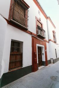a white building with a red door and windows at One & Lux Casa Maravilla in Seville