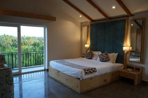 een slaapkamer met een groot bed en een balkon bij Corbett Selva Resort By DevStayZ in Rāmnagar +141 foto's