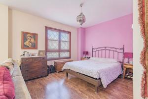 een slaapkamer met roze muren en een bed en een bank bij Luminoso Alhambra View Suite - El Laurel in Granada