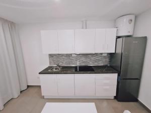 a kitchen with white cabinets and a refrigerator at Apartamento 1 vista mar, Las Américas, Costa Adeje, sx in Playa de las Americas