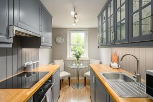 - une cuisine avec des placards noirs, un évier et une table dans l'établissement Castle View Hideaway, à Édimbourg