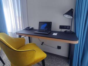 escritorio con ordenador portátil y silla amarilla en Mercure Epinal Centre en Épinal