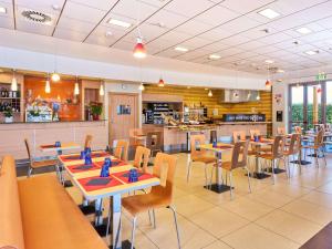 a restaurant with tables and chairs and a kitchen at Ibis Como in Grandate