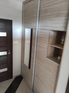 - une porte en bois dans une chambre avec un miroir dans l'établissement BarBen Apartman, à Mórahalom