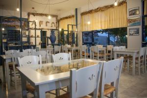 a dining room with white tables and white chairs at Argo Hotel in Agioi Apostoli