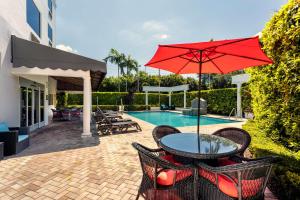 a patio with a table and an umbrella next to a pool at Hampton Inn West Palm Beach-Lake Worth-Turnpike in Lake Worth