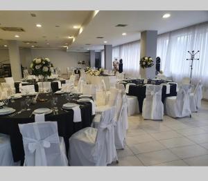 un salón de banquetes con mesas blancas y sillas blancas en Hotel Panonija en Sisak