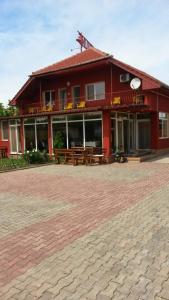 a red building with benches in front of it at Pensiunea San in Arad