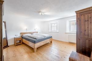 1 dormitorio con 1 cama y suelo de madera en Haus Alpenblick, en Oetz