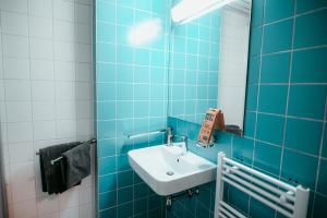 Baño de azulejos azules con lavabo y espejo en Vienna Shopping Center 14 Apartment, en Viena