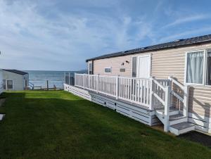 a house with a large deck and the ocean at Swift Mosselle Pitch 24 Creek Caravan Park dog friendly in Ringstead +37 photos