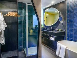 uma casa de banho com uma banheira e um espelho. em Pullman Santiago El Bosque em Santiago