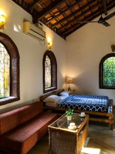 um quarto com uma cama, um sofá e janelas em Siolim Villa Goa 3 bhk em Siolim