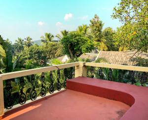 um banco vermelho sentado em cima de uma varanda em Siolim Villa Goa 3 bhk em Siolim