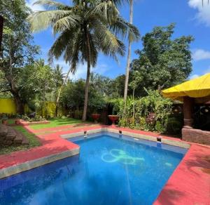 uma piscina num resort com palmeiras em Siolim Villa Goa 3 bhk em Siolim