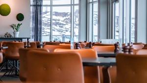 een eetkamer met stoelen, tafels en ramen bij Best Western Plus Hotel Ilulissat in Ilulissat