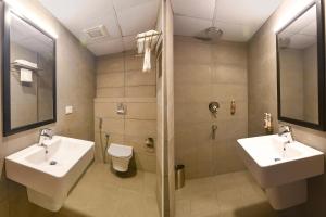 a bathroom with two sinks and a shower and a toilet at FabHotel Sayeeda International in Kolkata