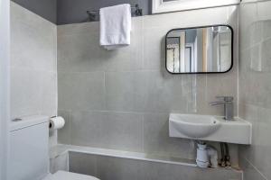 ein Badezimmer mit Waschbecken und Spiegel in der Unterkunft Stunning 3BR House w Garden & Parking in Richmond in Kew Gardens + 24 Fotos