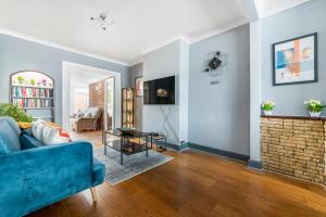 ein Wohnzimmer mit einer blauen Couch und einem Kamin in der Unterkunft Stunning 3BR House w Garden & Parking in Richmond in Kew Gardens