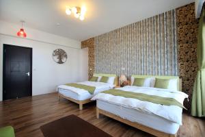 sypialnia z 2 łóżkami i ścianą z logami w obiekcie Chiyafonchin B&B w mieście Hualian