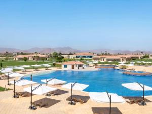a large swimming pool with white umbrellas and chairs at Rixos Golf Villas And Suites Sharm El Sheikh in Sharm El Sheikh