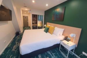 um quarto com uma cama grande e uma parede verde em La Quinta by Wyndham Ellerslie Auckland em Auckland