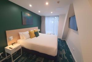 Un dormitorio con una cama grande y una pared verde en La Quinta by Wyndham Ellerslie Auckland en Auckland