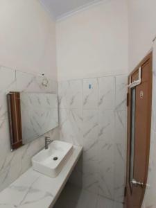 ein weißes Badezimmer mit einem Waschbecken und einem Spiegel in der Unterkunft d Ha'te in Tasikmalaya