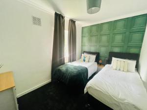 a bedroom with two beds and a green wall at Mitchell Apartment by Klass Living Coatbridge in Coatbridge