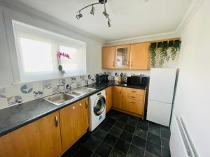 a kitchen with a sink and a refrigerator at Mitchell Apartment by Klass Living Coatbridge in Coatbridge