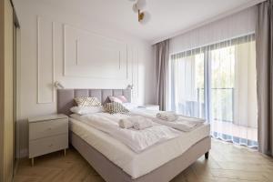 a white bedroom with a large bed with towels on it at Ogrody Pieniawskie Apartament Paryski in Polanica-Zdrój