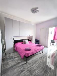 Un dormitorio con una cama rosa con sábanas moradas en Casa Viola - Al Centro en Taormina