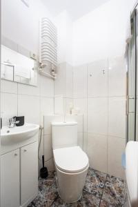 a white bathroom with a toilet and a sink at Park Praski Standard Studio in Warsaw