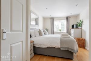 a white bedroom with a large bed with white pillows at StarHost Residences - Modern 2 bed apartment at Imperial Court, Newbury in Newbury