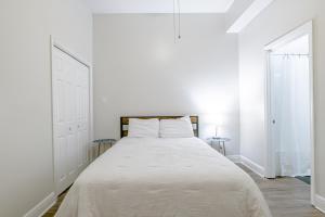 a white bed in a white bedroom with two tables at Newly Renovated Downtown Apartment in the Historic District, Quiet Street! in Mobile