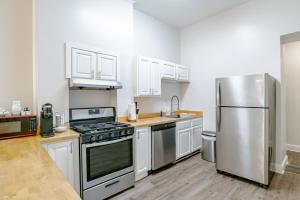 a kitchen with white cabinets and a stainless steel refrigerator at Newly Renovated Downtown Apartment in the Historic District, Quiet Street! in Mobile