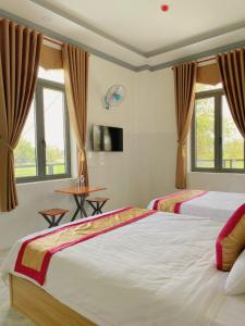 a bedroom with two beds and a table and windows at Lak village in Lien Son