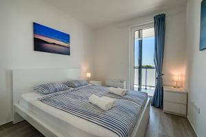 Un dormitorio blanco con una cama grande con sábanas azules y blancas. en Villa Miri III en Privlaka