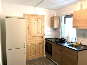 a kitchen with a white refrigerator and a wooden door at Monteur-Haus Linde in Biesenthal