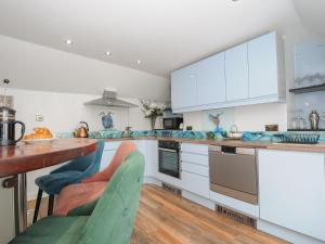 a kitchen with white cabinets and a wooden table at Moon's Cottage in Fowey