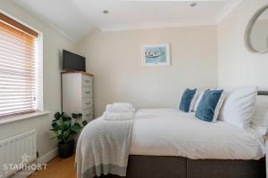 Schlafzimmer mit einem Bett mit weißer Bettwäsche und blauen Kissen in der Unterkunft Smart 2 Bedroom Apartment in Newbury in Newbury