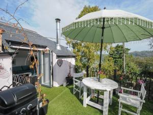 eine Terrasse mit einem Tisch und einem grünen Sonnenschirm in der Unterkunft Moon's Cottage in Fowey